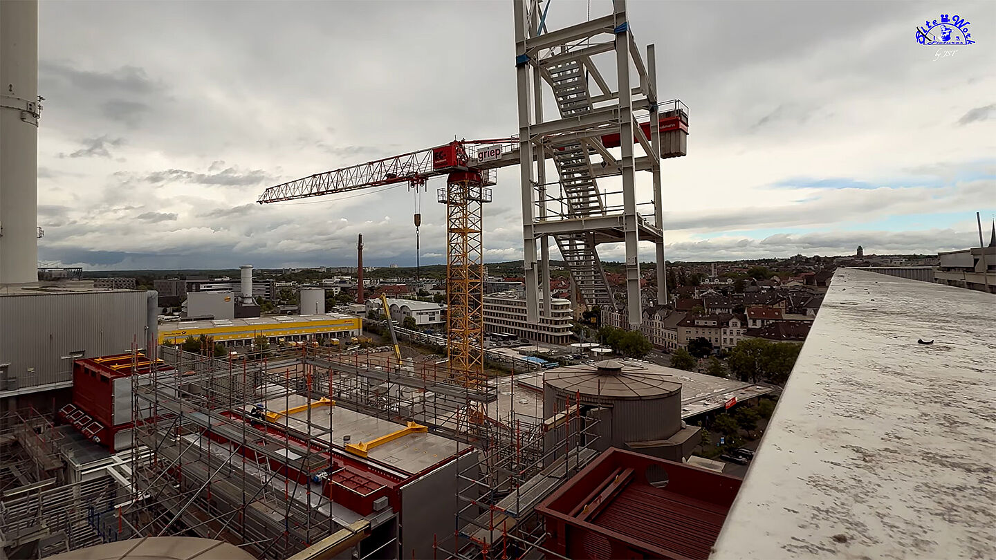 Städtische Skyline mit Industriegebäuden und Wolkenkratzern bei bedecktem Himmel.