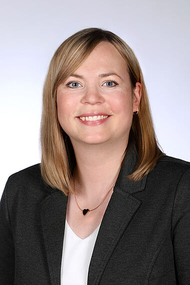 Frau in Anzug, lächelnd, professionelles Porträt.