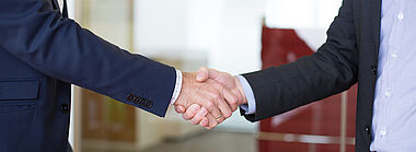 Ein Handschlag zwischen zwei Personen in Anzügen.