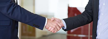 Ein Handschlag zwischen zwei Personen in Anzügen.