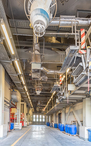 Lagerhalle mit Regalen, Containern und einer Krananlage im Hintergrund.