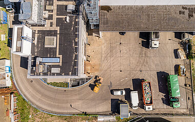 Baustellennähe mit Baugeräten und Lastwagen aus Vogelperspektive.