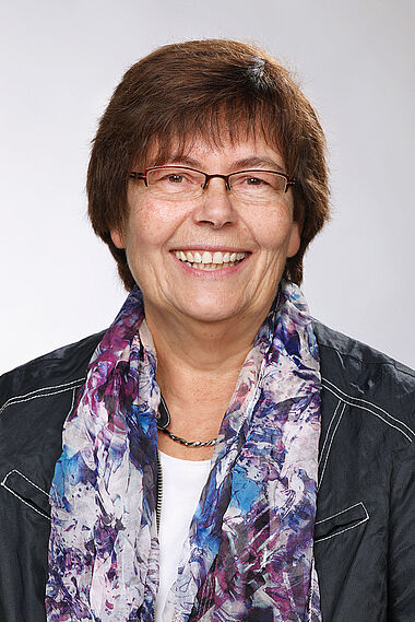 Frau in schwarzer Jacke und Schal, professionelles Porträt.