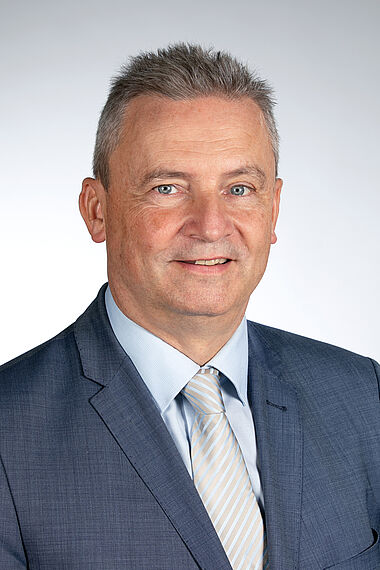 Mann im Anzug, lächelnd, für ein Firmenporträt.