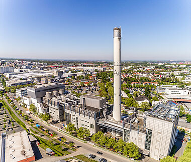 Industrieanlage mit Kamin und technischer Infrastruktur in städtischer Umgebung.