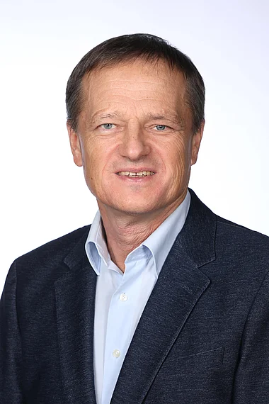 Ein Mann im Anzug und Hemd, professionelles Porträt.