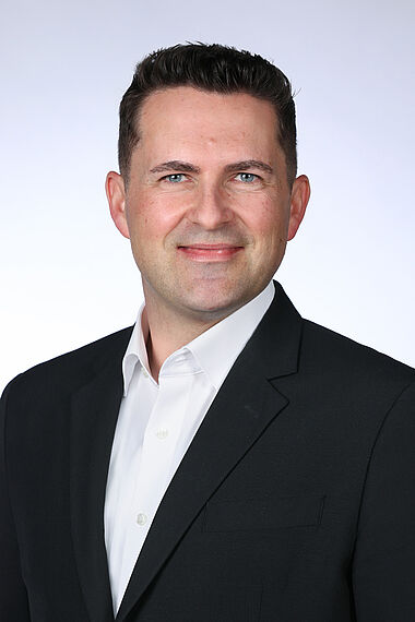 Professioneller Mann im Anzug, lächelnd, für ein Porträt.