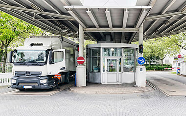 Lastkraftwagen fährt durch einen Kreisverkehr mit Sicherheitsvorkehrungen.