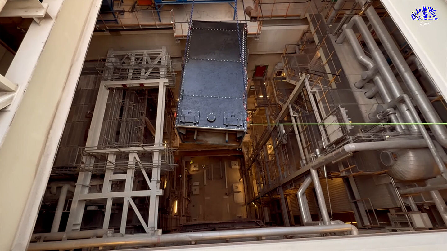 Technische Anlage mit Rohren und Behältern im Innenraum sichtbar.