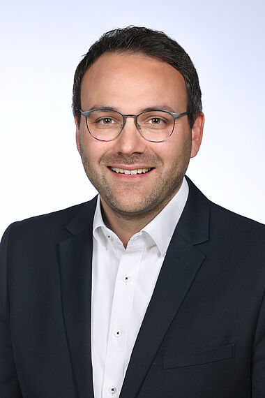 Porträt eines Mannes im Anzug mit Brille, professionelles Erscheinungsbild.