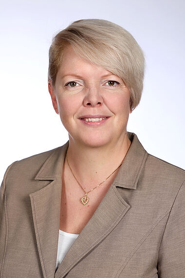 Professionelle Porträt einer Frau in einem hellen Anzug.