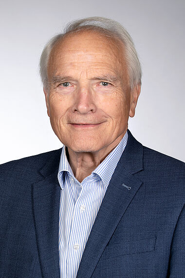 Porträtfoto eines lächelnden Mannes im Anzug.